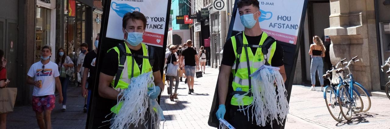 Masken werden in Amsterdam an Passanten verteilt.