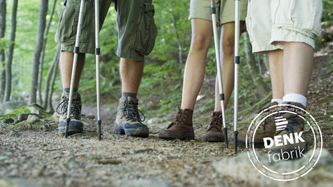 Die Beine von drei Menschen mit Wanderschuhen im Wald