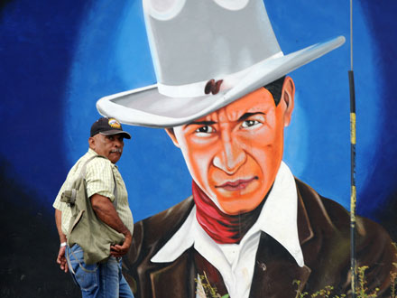 Ein Mann läuft an einem Wandgemälde von Augusto César Sandino vorbei.