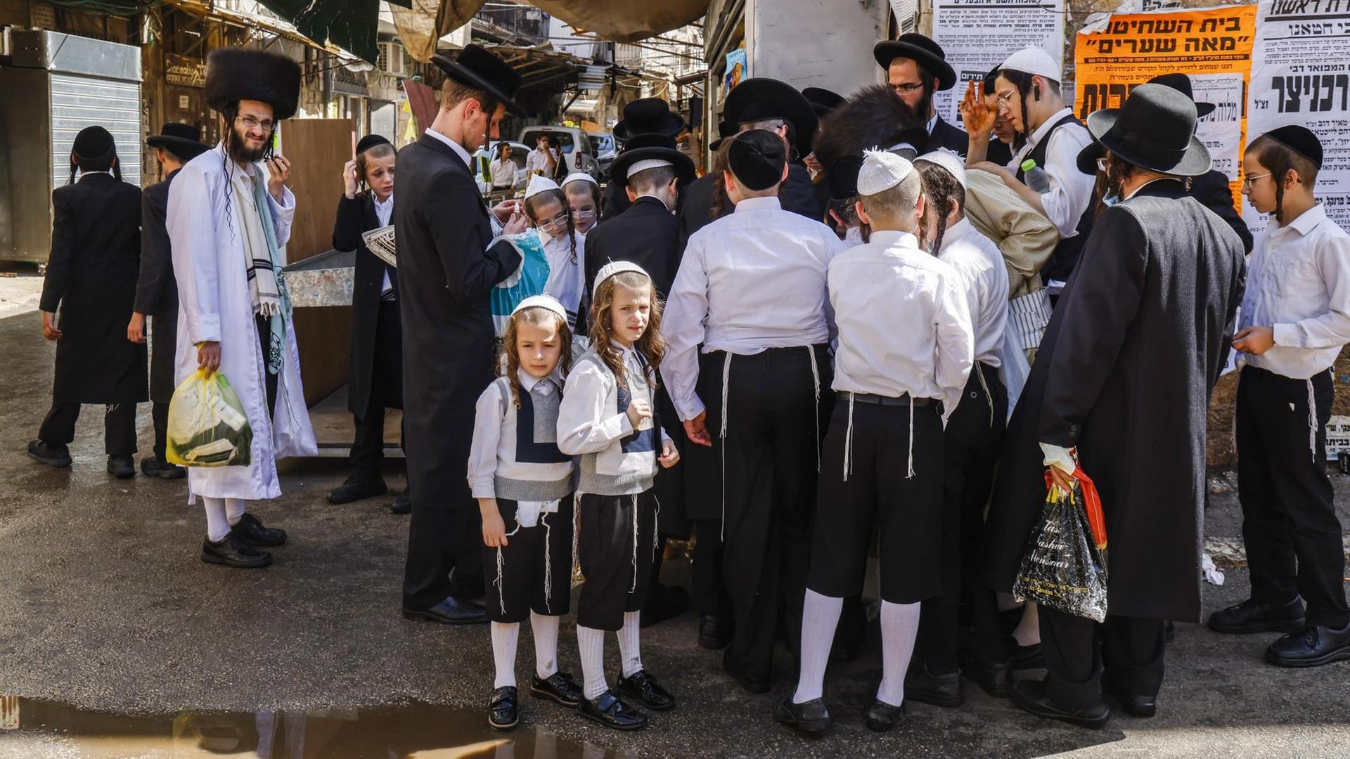 Ultraorthodoxe jüdische Männer und Jungen, einige aufgrund der COVID-19-Coronavirus-Pandemie in Masken gekleidet, stehen an einer Straßenecke in Jerusalem