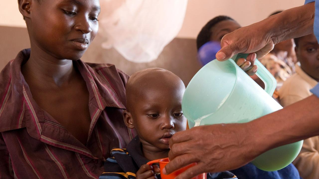 In dem Land Burundi bekommen Menschen von Helfern Milch.