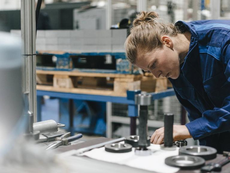 Young woman working as a skilled worker in a high tech company, controlling production machine model released Symbolfoto property released
