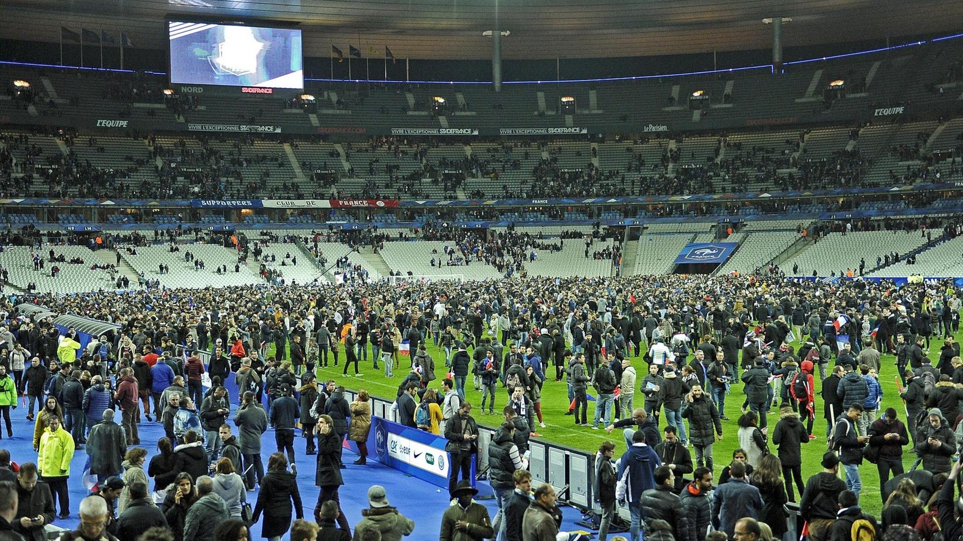 Hunderte Menschen auf dem Rasen des Stade de France, die Ränge sind größtenteils leer.