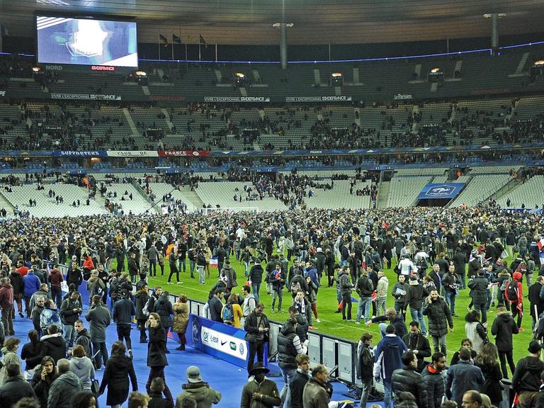 Hunderte Menschen auf dem Rasen des Stade de France, die Ränge sind größtenteils leer.