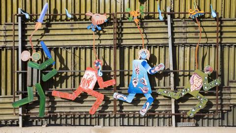 Kunstwerk auf der mexikanischen Seite des Grenzzauns, der die USA von Mexiko trennt, zeigt einen US-Grenzschutzpolizisten, der mit Schlagstock mehrere flüchtende Personen verfolgt, aufgenommen in Nogales, Sonora, Mexiko