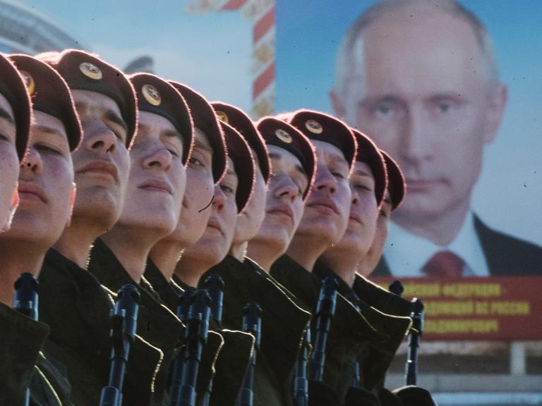 Russische Truppen vor einem Plakat des russischen Präsidenten Wladimir Putin