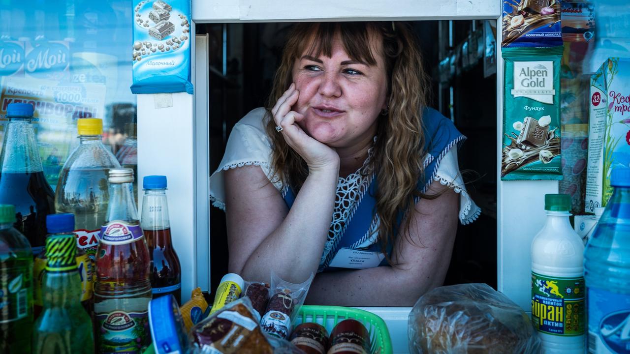Eine russische Frau schaut aus dem Fenster ihres kleinen Ladens.