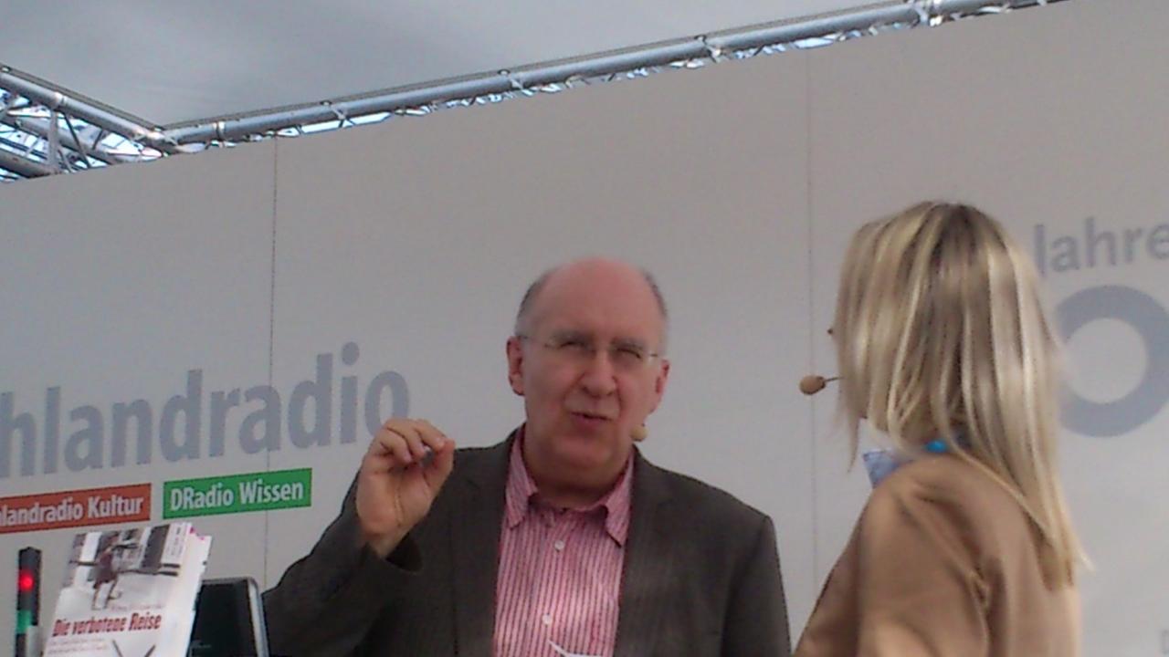 "Andruck"-Redakteurin Catrin Stövesand im Gespräch mit Peter Wensierski am Deutschlandradio-Stand auf der Leipziger Buchmesse. Auf dem Tisch vor den Interviewpartnern ist sein Buch "Die verbotene Reise" aufgestellt.