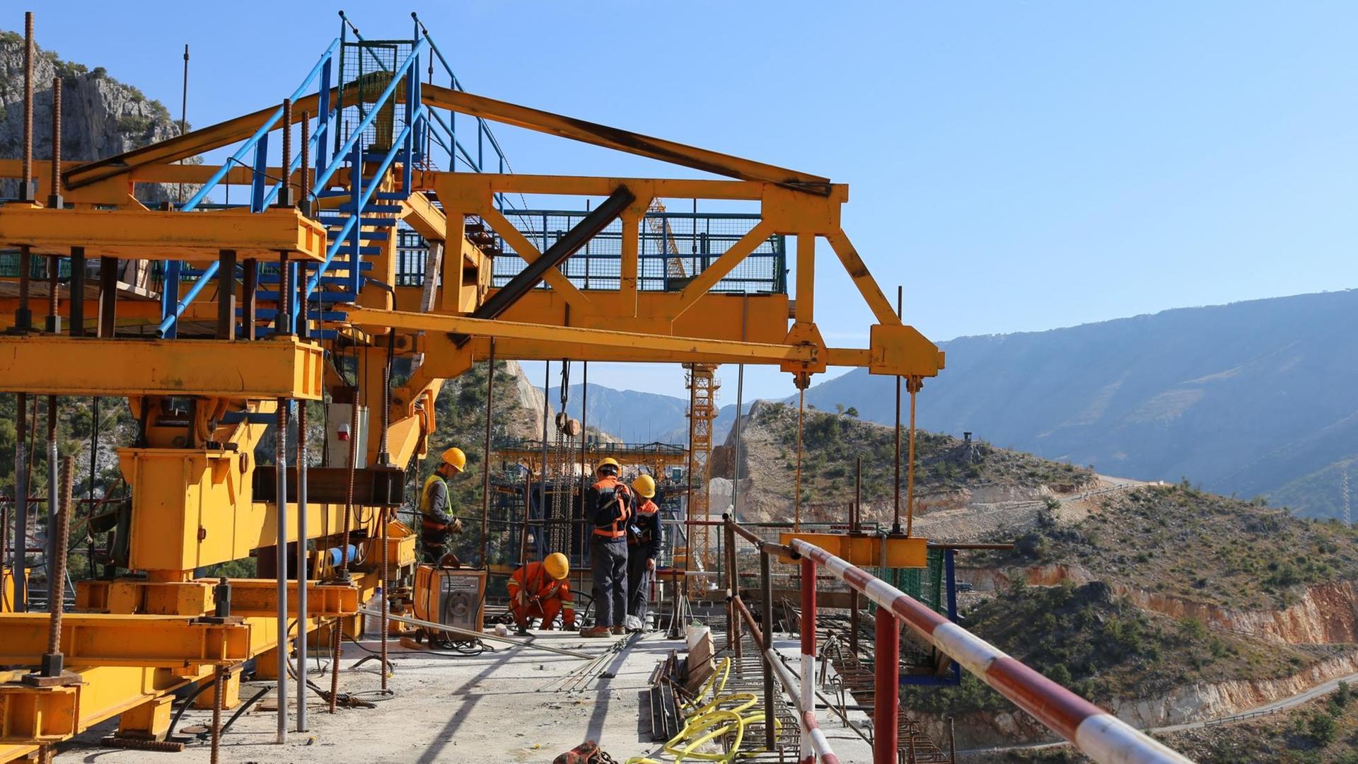 Bauarbeiter stehen auf einer großen Baustelle in Montenegro, wo China die erste Autobahnstrecke des Landes finanziert.