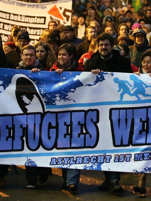 Demonstration unter dem Motto "Willkommen im Abendland - Rostock für alle" am 05.01.2015 in Rostock. Im Vordergrund ein Plakat auf dem "Refugees Welcome - Asylrecht ist Menschenrecht" steht.