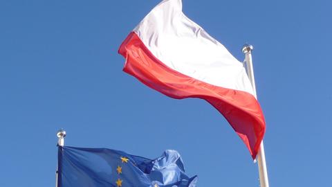 Die Europafahne und die Flagge Polens vor blauem Himmel