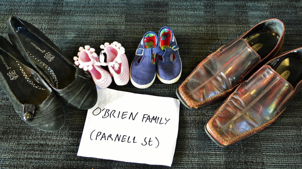 Ein Paar Damen- und Herrenschuhe sowie Schuhe von zwei Kindern mit einem Zettel auf dem O'Brien Family und Parnett Street zu lesen ist.