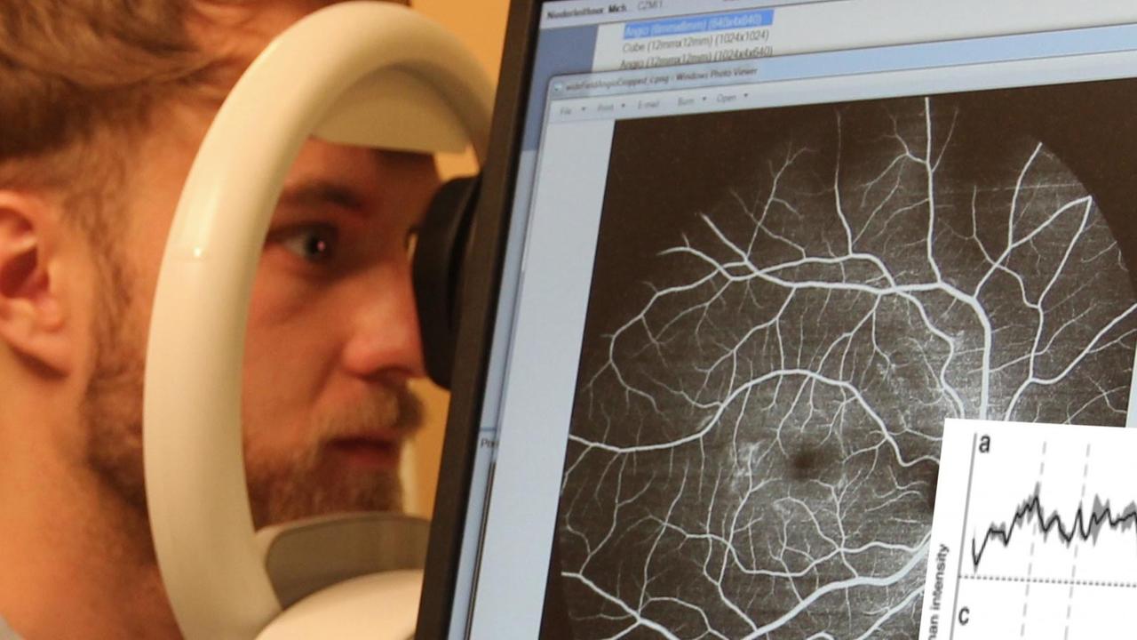 Ein Mann am Augenscanner, der mit Hilfe von Lasern Augenkrankheiten erkennen könnte