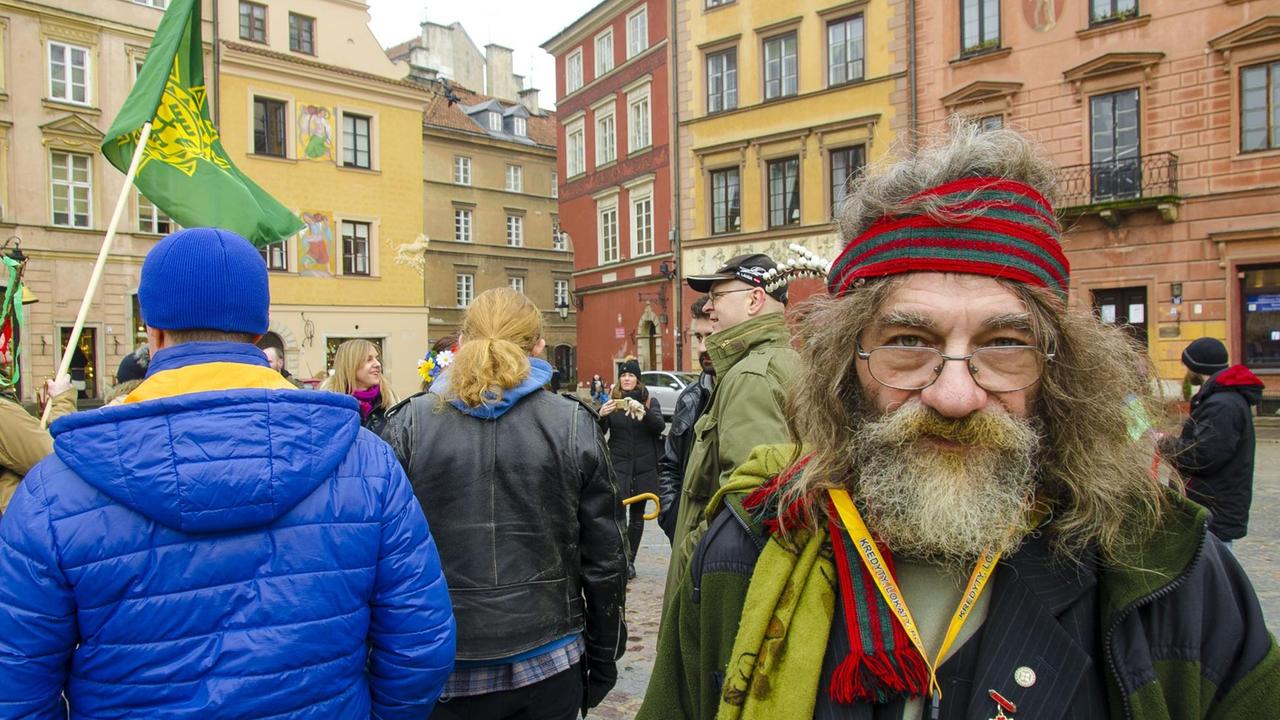 Älterer Mann auf dem Marktplatz der Warschauer Altstadt, in eienr Gruppe jüngerer Polen