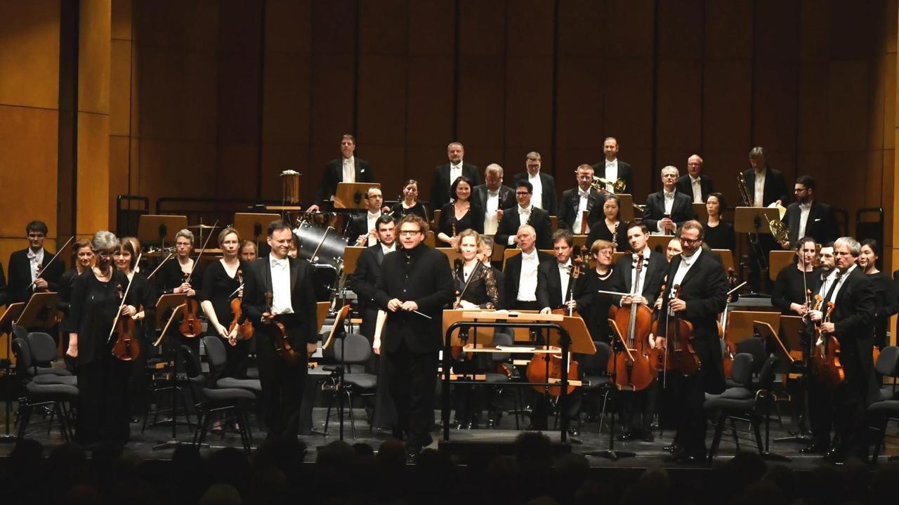 Das Orchester ist für Beifall aufgestanden und umsteht seinen Chefdirigenten Marcus Bosch.