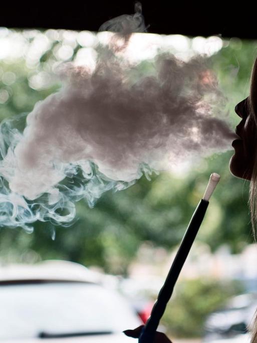 Eine junge Frau raucht in einer Shisha-Bar in Berlin eine Shisha-Pfeife.