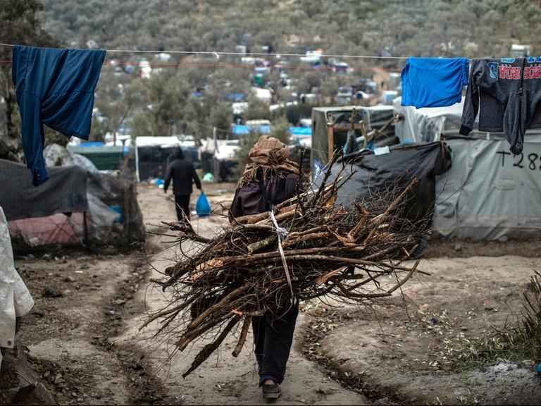 Ein Flüchtling trägt Holz auf dem Rücken, in einem provisorischen Lager neben dem Lager in Moria.