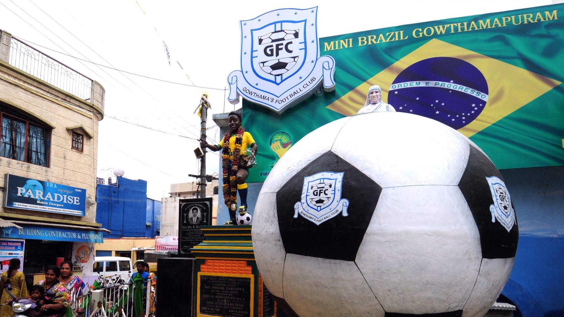 Ein riesiger Fußball und eine Brasilien-Flagge schmücken während der Fußballweltmeisterschaft eine Straßenkreuzung in Bangalore in Indien, wo dieser Sport allmählich auch eine größere Verbreitung findet. Ein riesiger Fußball und eine Brasilien-Flagge schmücken während der Fußballweltmeisterschaft eine Straßenkreuzung in Bangalore in Indien, wo dieser Sport allmählich auch eine größere Verbreitung findet.