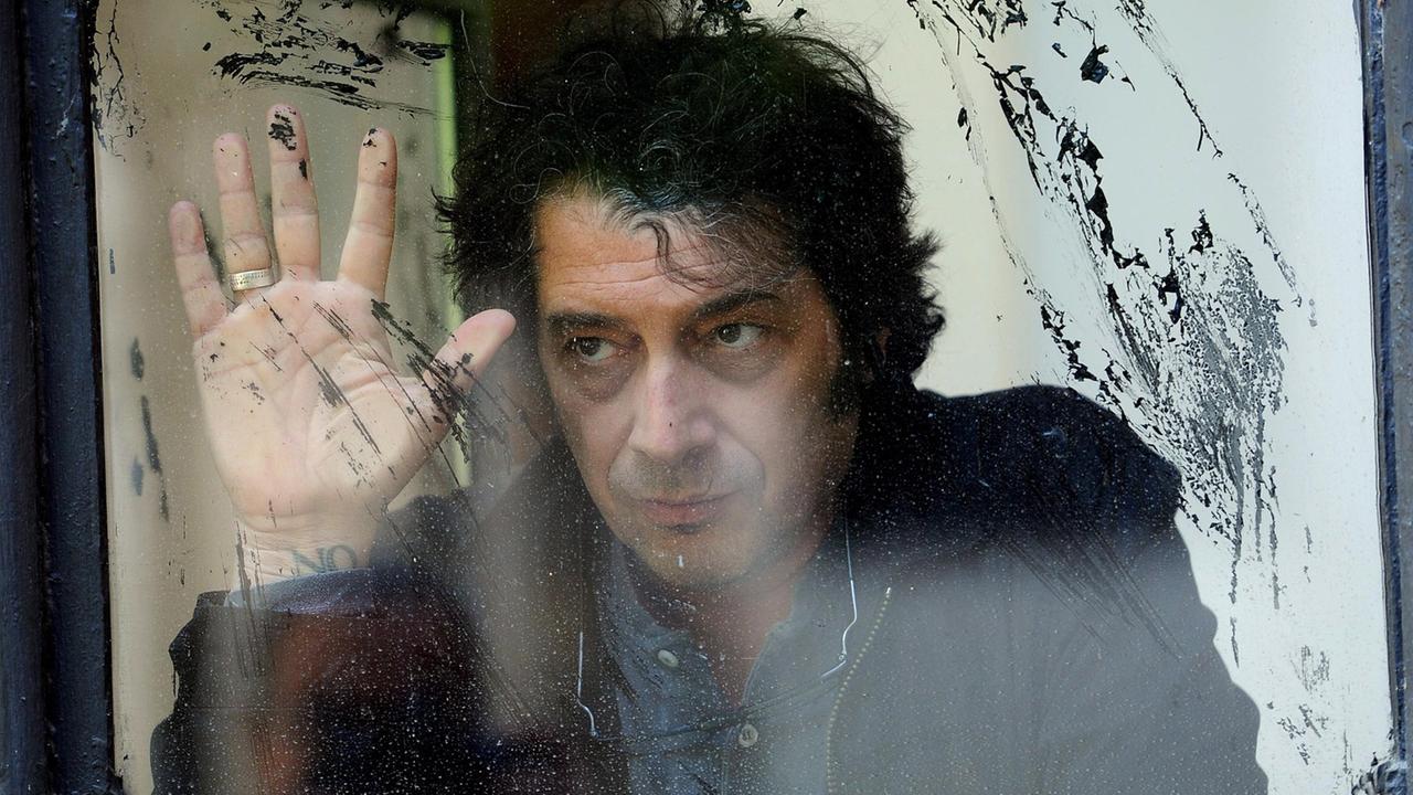 Sandro Veronesi, Schriftsteller, aufgenommen hinter einer schnutzigen Glasscheibe.