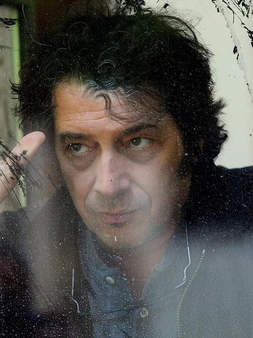 Sandro Veronesi, Schriftsteller, aufgenommen hinter einer schnutzigen Glasscheibe.