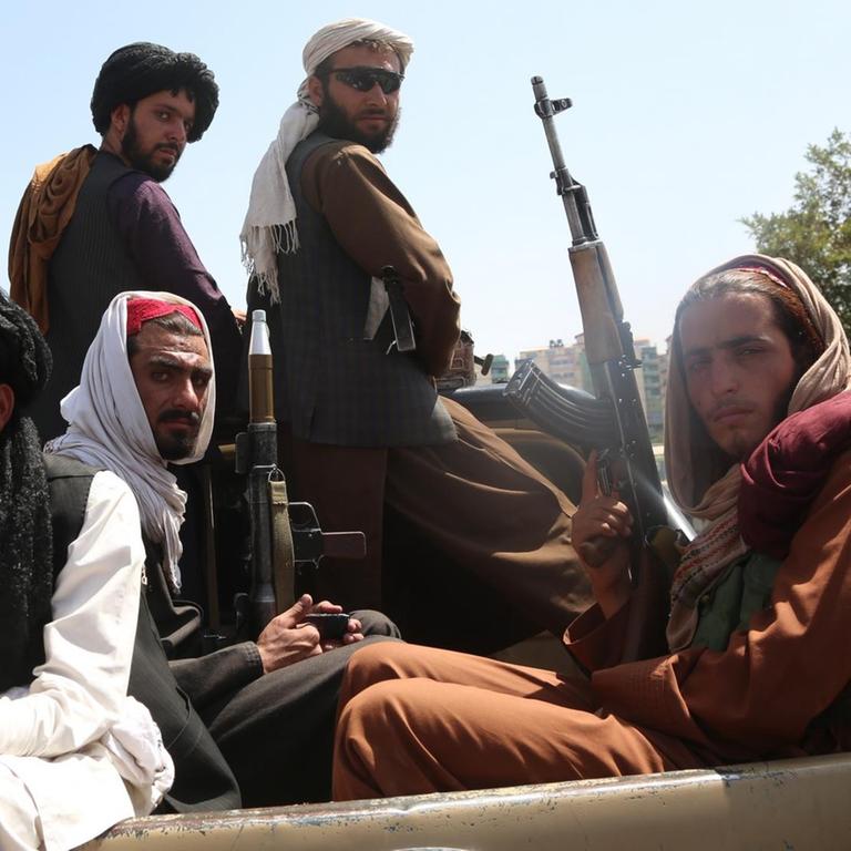 Taliban-Kämpfer sitzen in einem Fahrzeug in Kabul einmarschiert