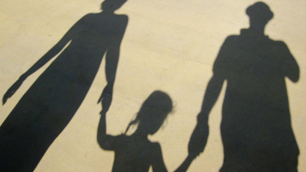 Der Schatten einer Familie, die sich an der Hand hält.