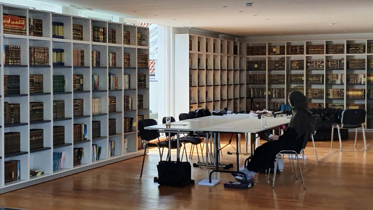 Die Innenräume des Islamkolleg Deutschland in Osnabrück. Hier sollen Frauen und Männer ausgebildet werden. An den Wänden stehen Bücherregale, in der Mitte ein Tisch, an der eine Frau sitzt.