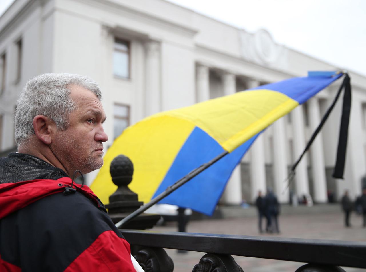 Ein Mann mit einer Ukraine-Flagge wartet vor dem Parlament in Kiew.