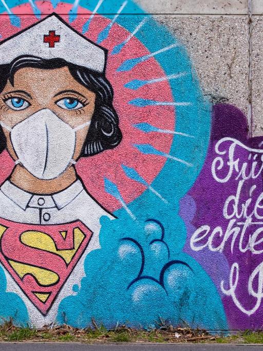 Ein Graffitti des Künstlers Kai 'Uzey' Wohlgemuth zeigt eine Krankenschwester als Superwomanan einer grauen Wand in Hamm. Dazu steht "Für die echten Helden".
