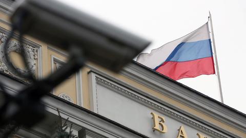 Auf der russischen Zentralbank in Moskau weht eine Russland-Fahne, davor ist eine Überwachungskamera zu sehen