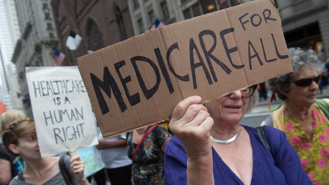 Menschen protestieren im Juli 2017 in New York für die allgemeine Krankenversicherung und halten Schilder hoch.