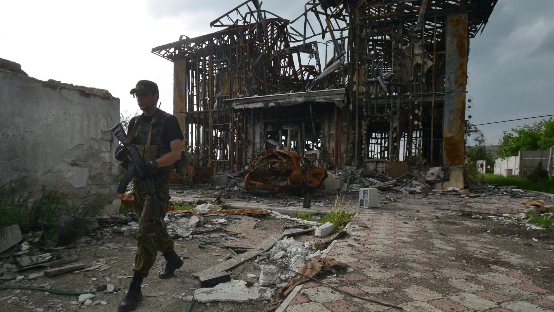 Ein ukrainischer Milizionär patroulliert vor der Ruine eines Hauses in der Nähe der Front im Osten der Ukraine