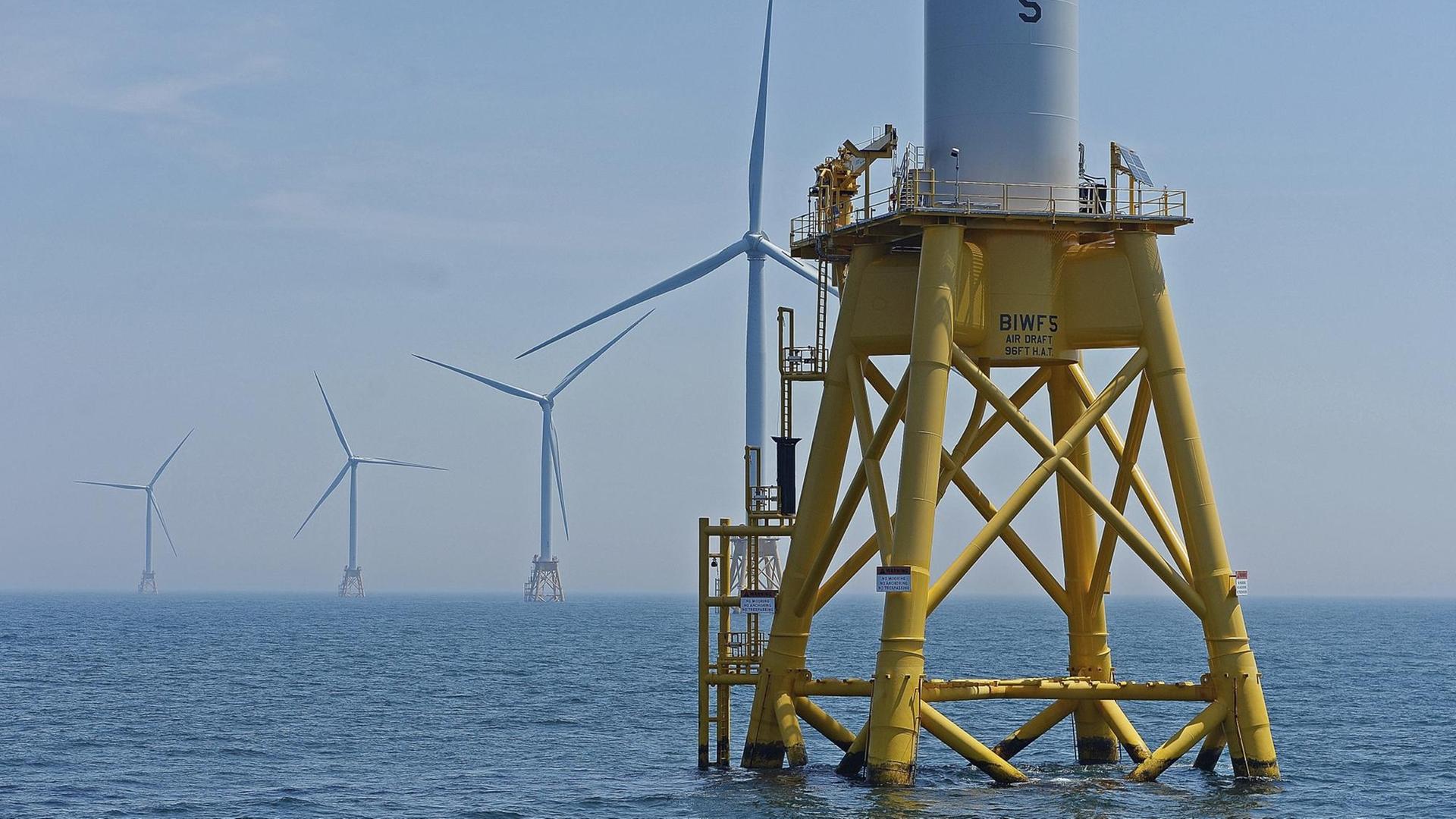 Aus dem Meer vor der Ostküste der USA ragen mehrere Stahlplattformen, auf denen große Windräder zur Stromerzeugung montiert sind.