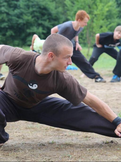 Auf einer Wiese trainieren Jugendliche Kung Fu. Im Vordergrund ist der Trainer zu sehen.