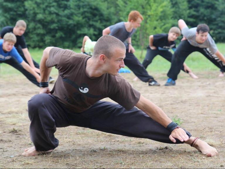 Auf einer Wiese trainieren Jugendliche Kung Fu. Im Vordergrund ist der Trainer zu sehen.