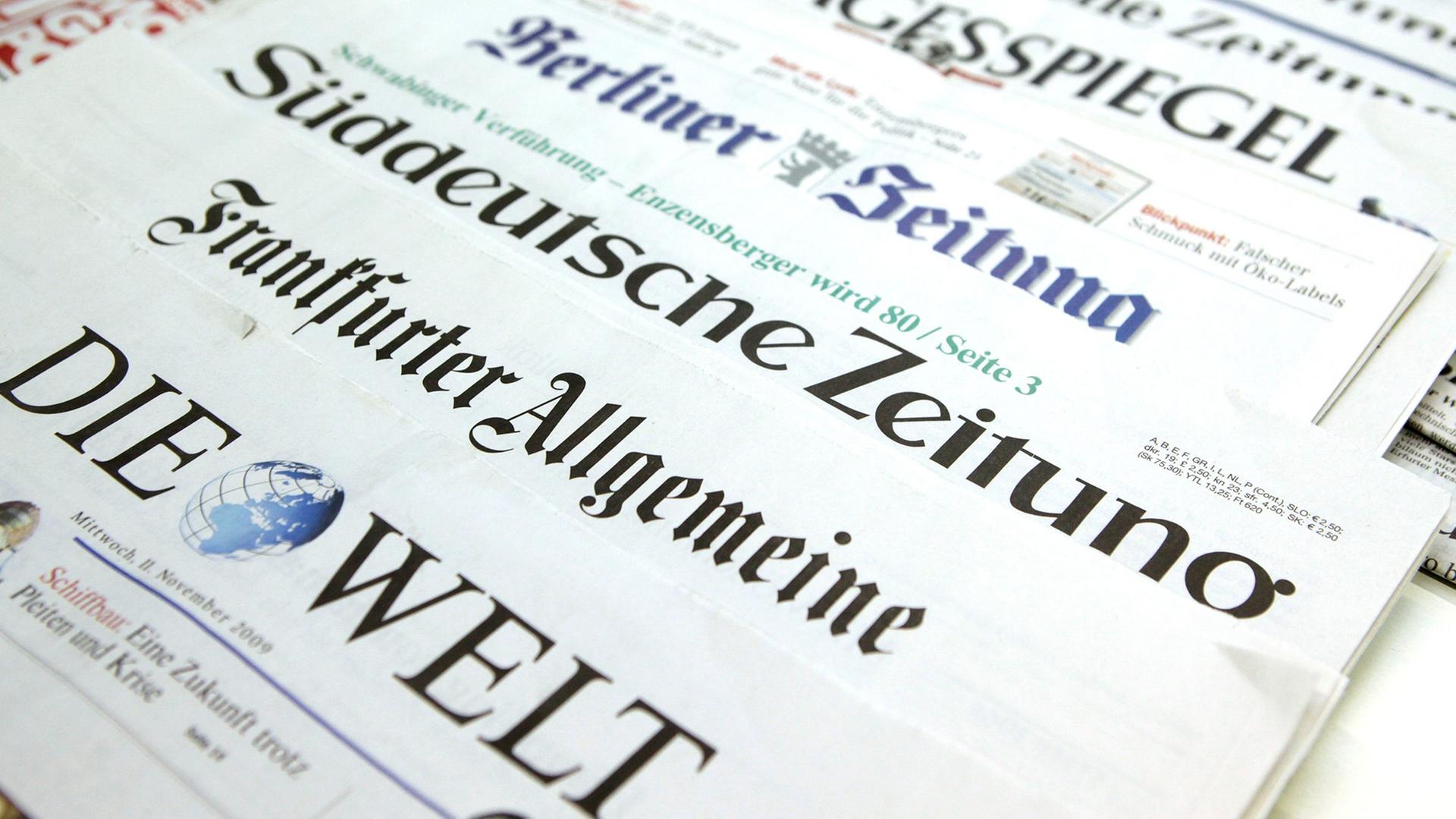 Auf einem Tisch liegen deutsche Tageszeitungen so versetzt, dass jeweils nur der Titel zu lesen ist, ganz vorne "Die Welt", "Frankfurter Allgemeine Zeitung" und "Süddeutsche Zeitung"