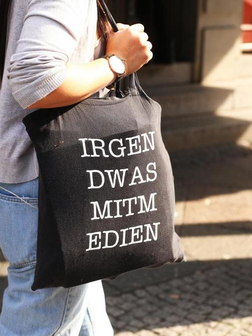 Eine junge Frau trägt am 28.09.2017 in Berlin im Stadtteil Mitte eine Jutetasche mit der Aufschrift "IRGEN DWAS MITM EDIEN" für "Irgendwas mit Medien".