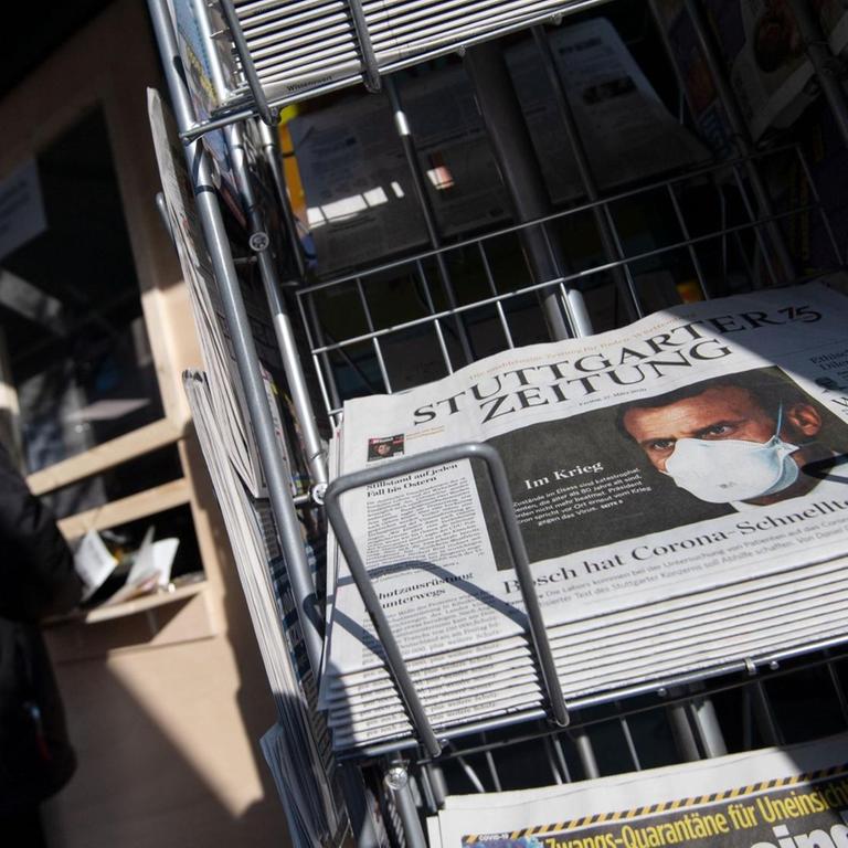 Zeitungen liegen in einem Ständer vor einem Einzelhandelsgeschäft 