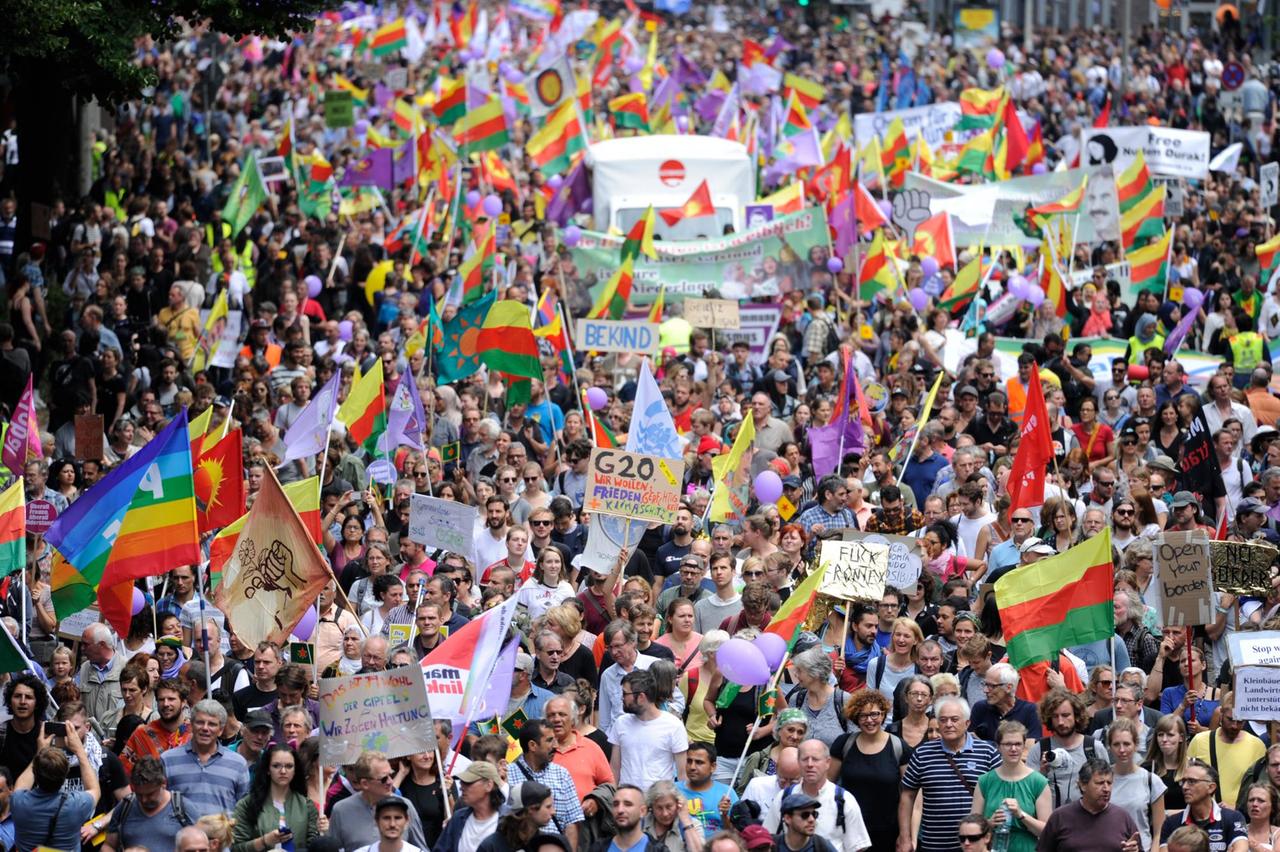 Ein Blick auf die Demonstrationsteilnehme, die viele bunte Fahnen und Banner tragen.