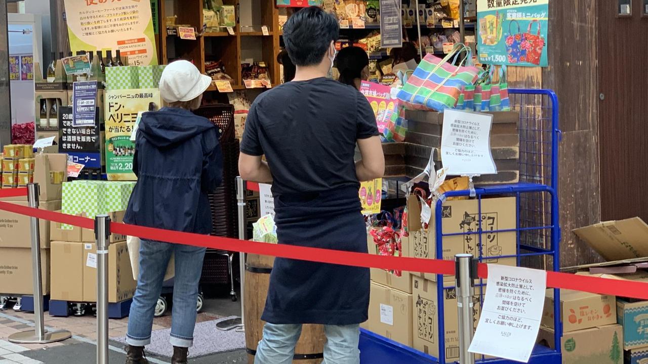 Kunden stehen in Abstand vor einem Laden in Tokio, Japan
