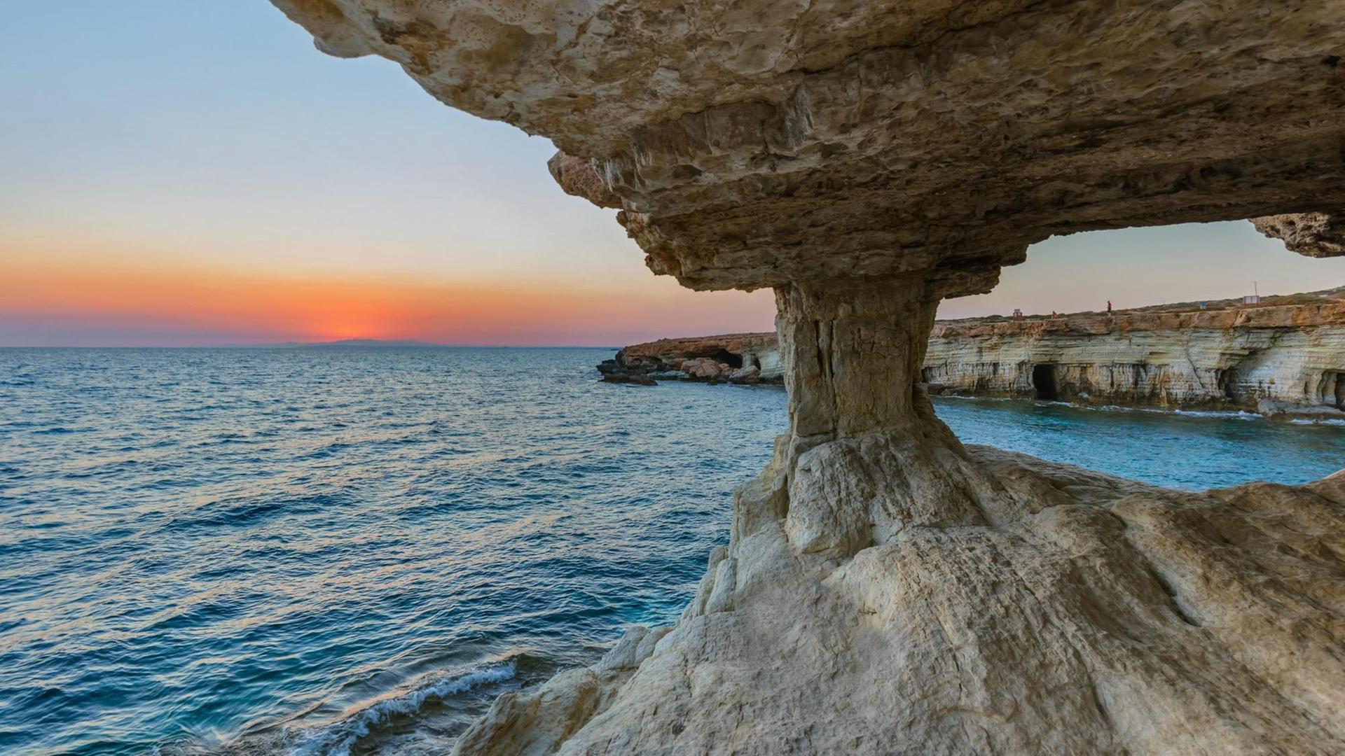 Blick von einer Meereshöhle in Ayia Napa auf Zypern über das das Meer und die Küste in der Abenddämmerung.