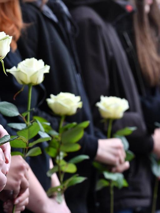 Bei einer Gedenkfeier vor dem Gutenberg-Gymnasium halten Schüler am 26.04.2017 in Erfurt (Thüringen) weiße Rosen in den Händen. 15 Jahre nach dem Amoklauf am Gutenberg-Gymnasium in Erfurt haben Schüler, Lehrer und Angehörige der Opfer gedacht. Mehrere hundert Menschen erinnerten an die zwölf Lehrer, zwei Schüler, die Sekretärin und den Polizisten, die bei der Tat getötet wurden.