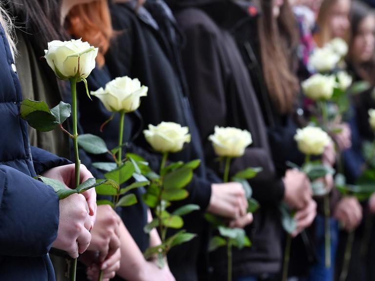 Bei einer Gedenkfeier vor dem Gutenberg-Gymnasium halten Schüler am 26.04.2017 in Erfurt (Thüringen) weiße Rosen in den Händen. 15 Jahre nach dem Amoklauf am Gutenberg-Gymnasium in Erfurt haben Schüler, Lehrer und Angehörige der Opfer gedacht. Mehrere hundert Menschen erinnerten an die zwölf Lehrer, zwei Schüler, die Sekretärin und den Polizisten, die bei der Tat getötet wurden.