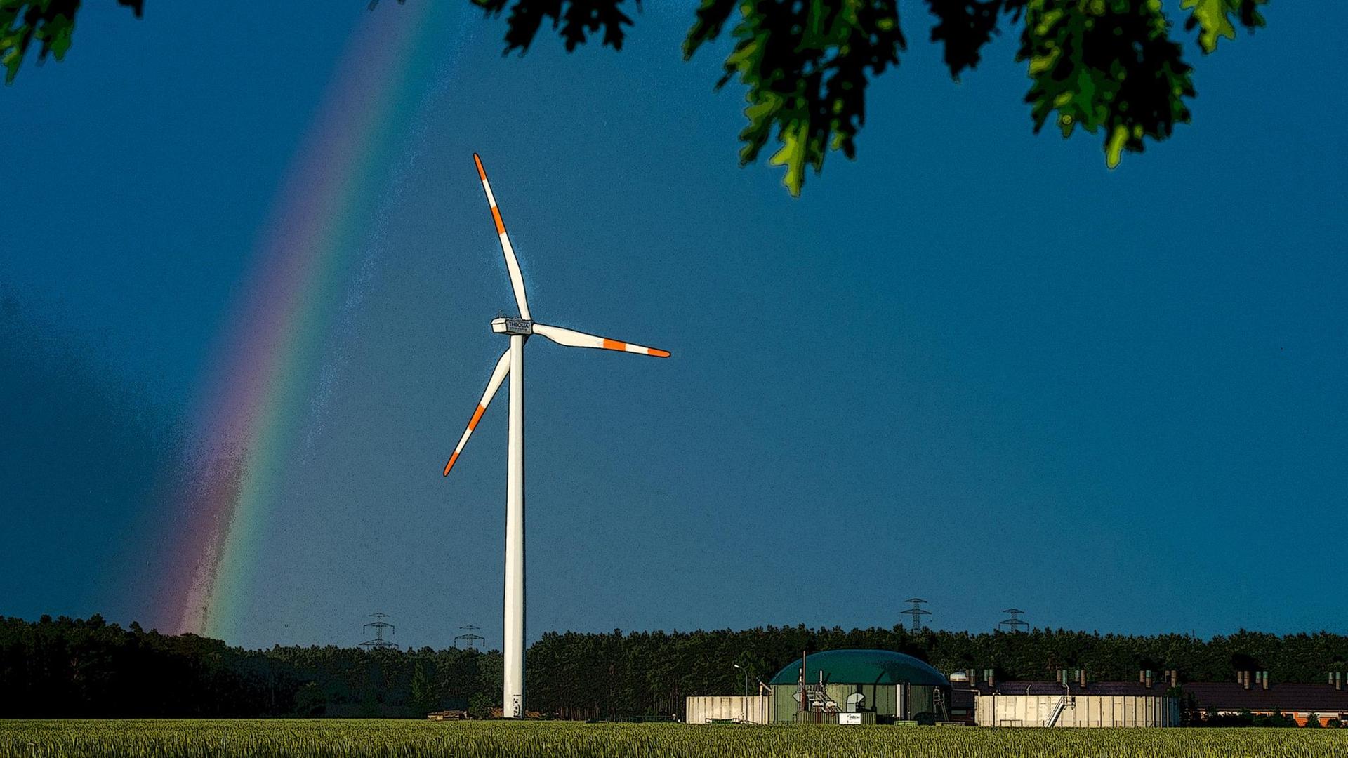 Ein Regenbogen leuchtet vor dunklen Gewitterwolken hinter einem Windrad im Landkreis Spree-Neiße nahe Peitz (Brandenburg).