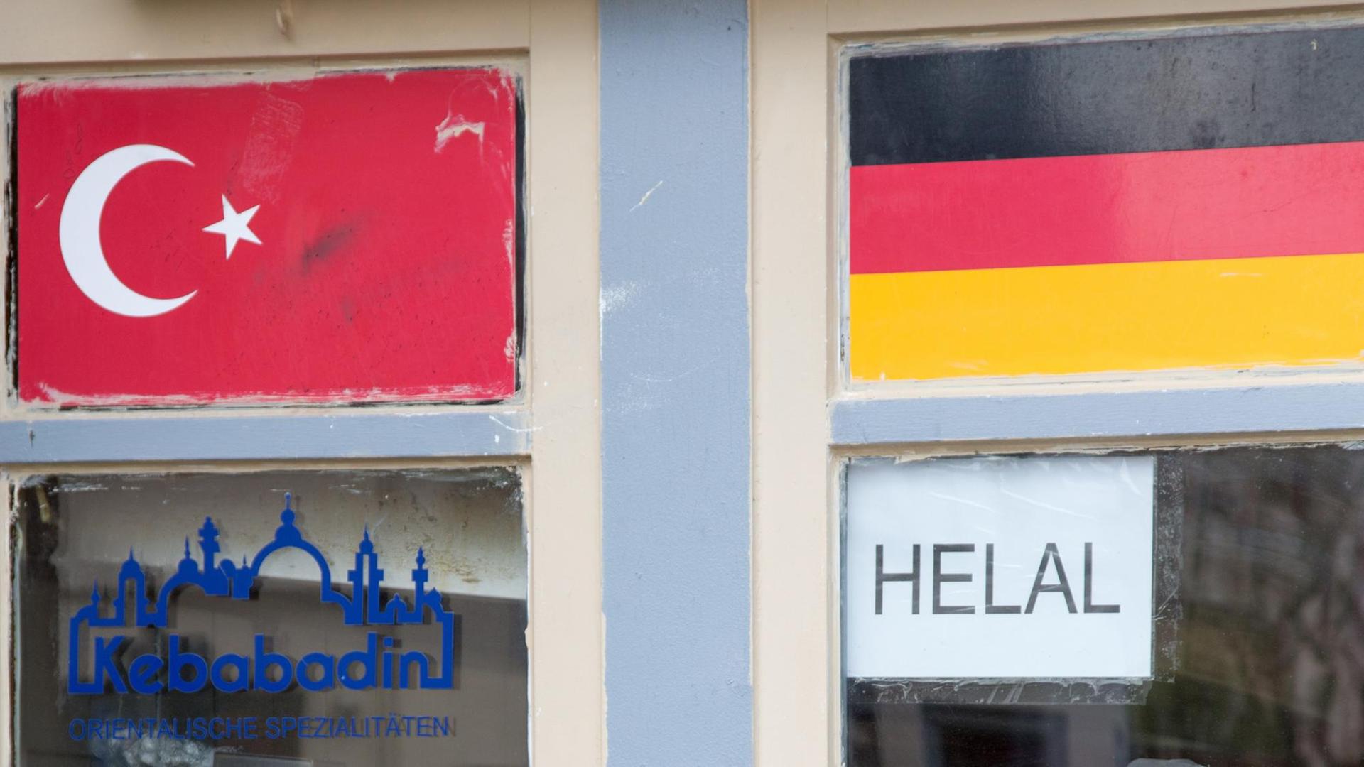 Eine türkische und eine deutsche Fahne am Fenster zu einem Imbiss.