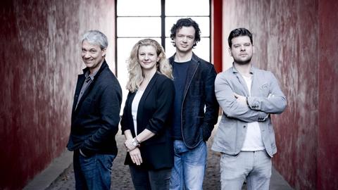 Das Bild zeigt das Pavel Haas Quartett in einem rot gestrichenem Hauseingang.