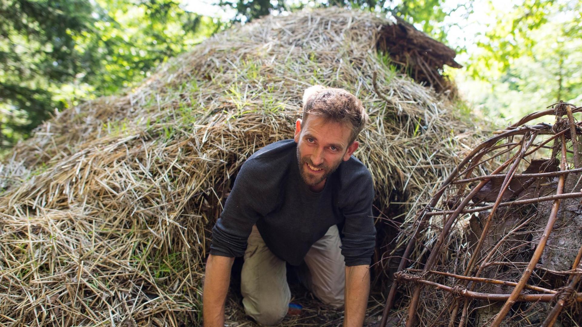 Marc Freukes kriecht am 12.08.2014 in einem Waldstück bei Grasellenbach-Hammelbach (Hessen) aus seinem Winterquartier. Freukes wohnt seit Anfang des Jahres in einem Tipi-Zelt im Wald. Foto: Uwe Anspach (zu lsw-Korr: «Zuhause im Tipi: «Ich brauche sehr wenig» vom 19.08.2014) | Verwendung weltweit