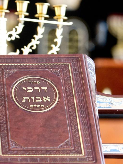 Ein jüdisches Gebetsbuch steh vor einer Menora.