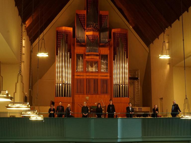 Acht Mitglieder des Chores stehen vor der Orgel in der Jesus-Christus-Kirche in Berlin-Dahlem.
