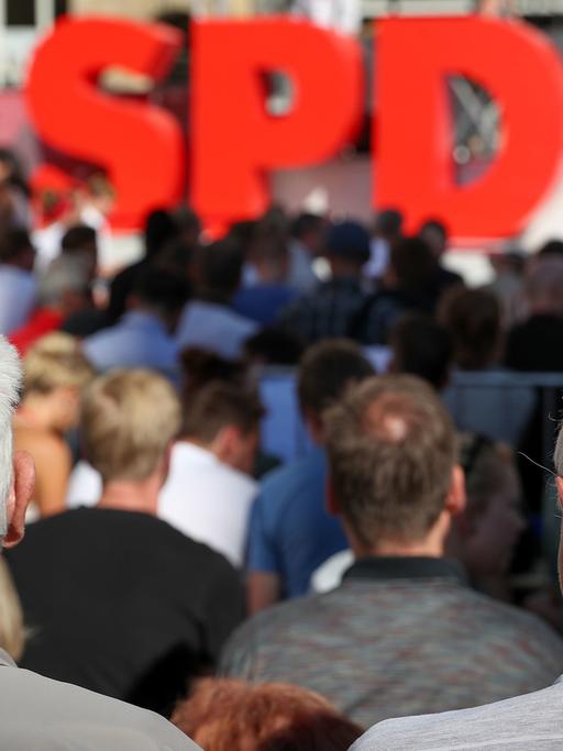Zwei grauhaarige Männer verfolgen eine Wahlkampfveranstaltung der SPD am 2017 auf dem Nikolaikirchhof in Leipzig, auf der Bühne stehen die drei großen roten Buchstanden "SPD"